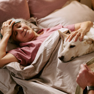Sick woman laying in bed with her dog