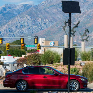 A red car stops in front of a Flock Safety camera.