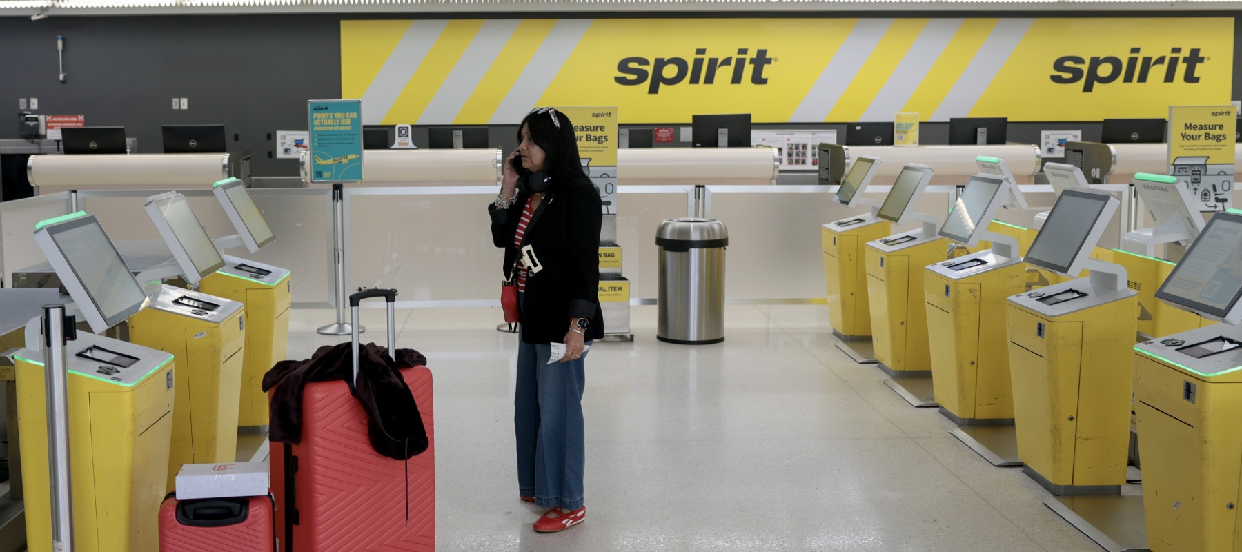 A woman speaks to a friend on her phone after her Spirit Airlines flight to Guatemala was canceled when the company went out of business.