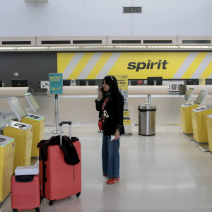 A woman speaks to a friend on her phone after her Spirit Airlines flight to Guatemala was canceled when the company went out of business.