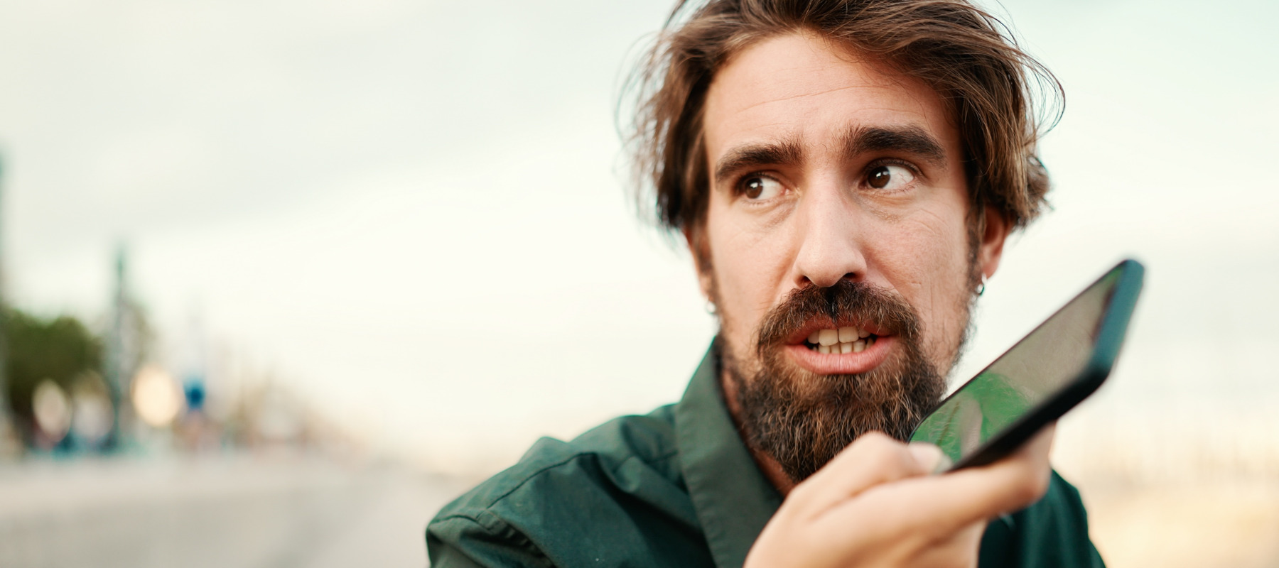 Man seen talking into his phone, looking off to the side of the camera and uncertain.