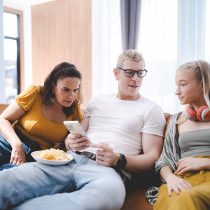 Young people sitting on couch looking at smartphone
