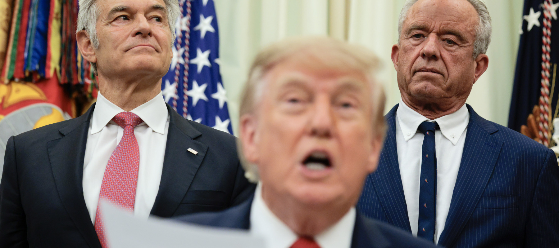 Medicare and Medicaid Administrator Mehmet Oz (L) and US Health and Human Services Secretary Robert F. Kennedy Jr. (R) listen as US President Donald Trump speaks.