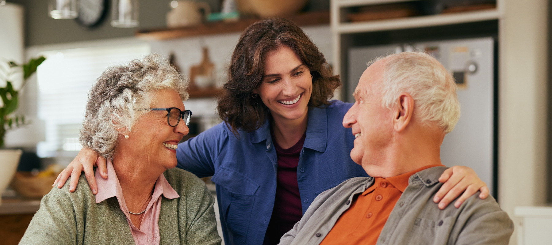 A young woman smiling between her two older parents at a breakfast table