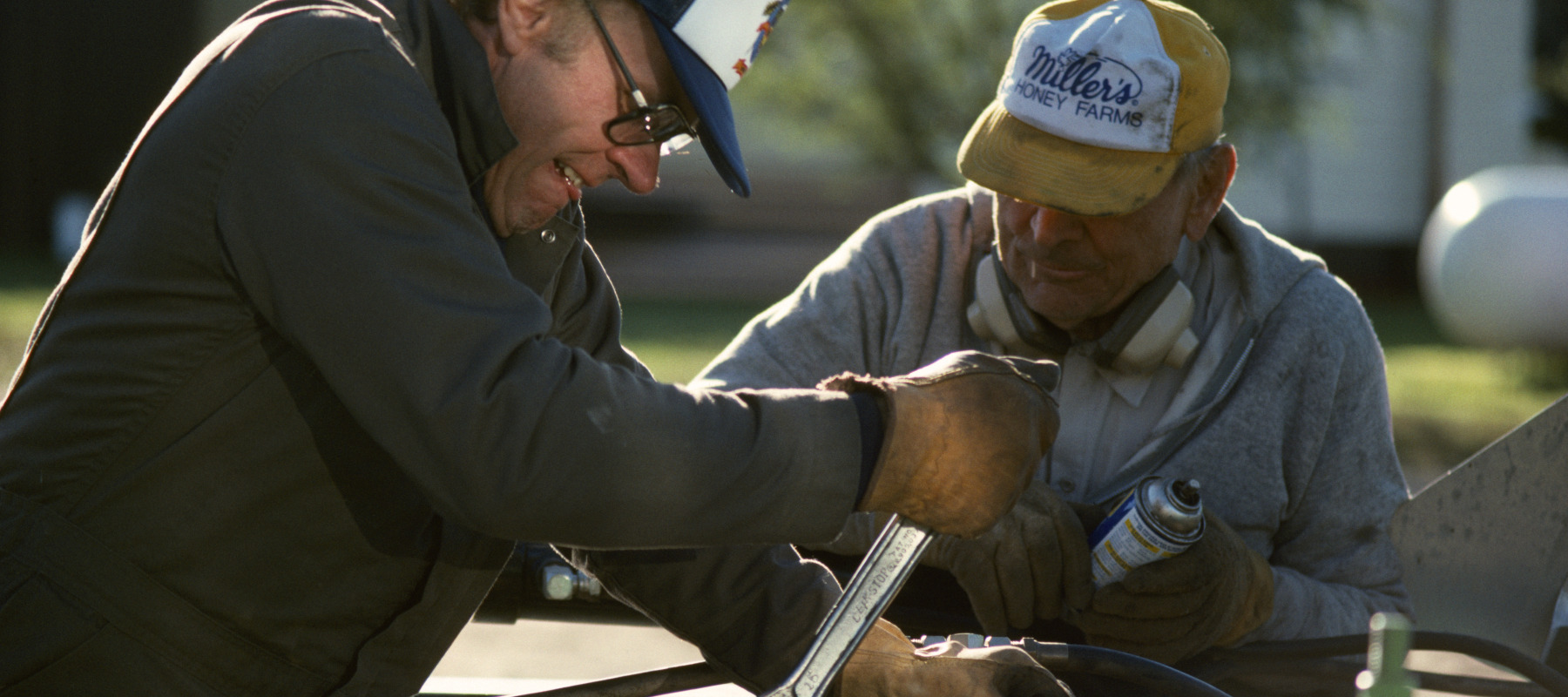 Two brothers, who are farmers, repair a plow on their property.