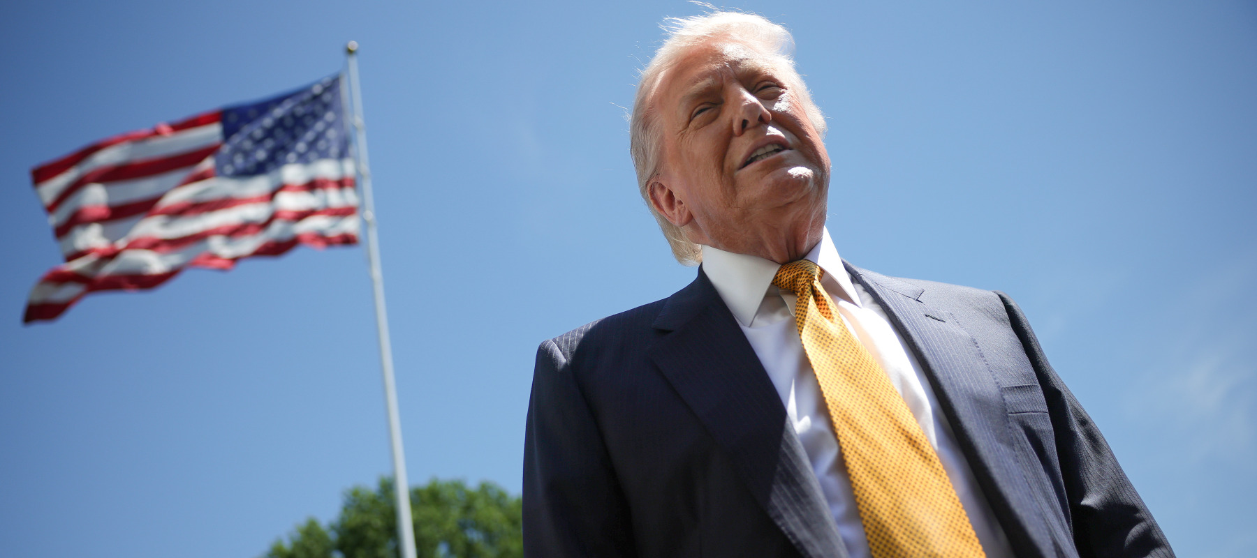 Trump speaks in front of the American flag to the press as he departs the White House.
