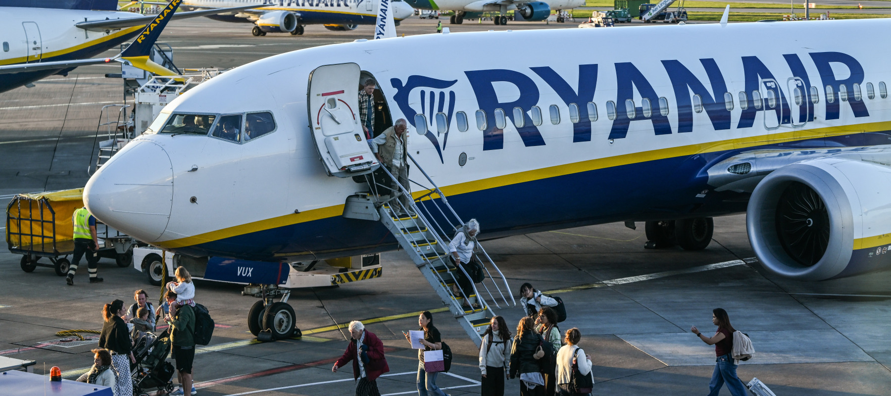Passengers disembark from a Ryanair flight on the busy airport apron while flight crew look out from the cockpit in September 2026.