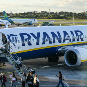 Passengers disembark from a Ryanair flight on the busy airport apron while flight crew look out from the cockpit in September 2026.
