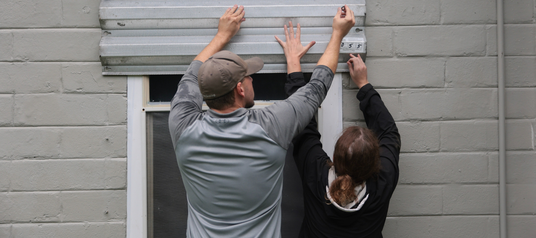Dan Conley and Suzanna Buchanan put up shutters before the arrival of Hurricane Isaias
