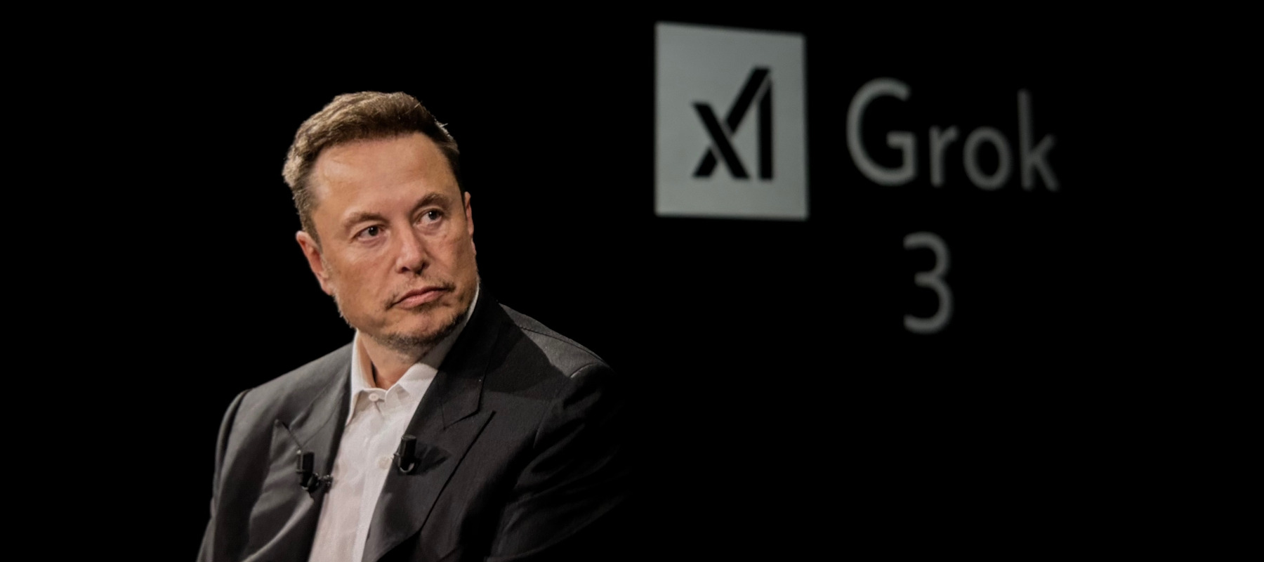 Elon Musk in front of Grok logo