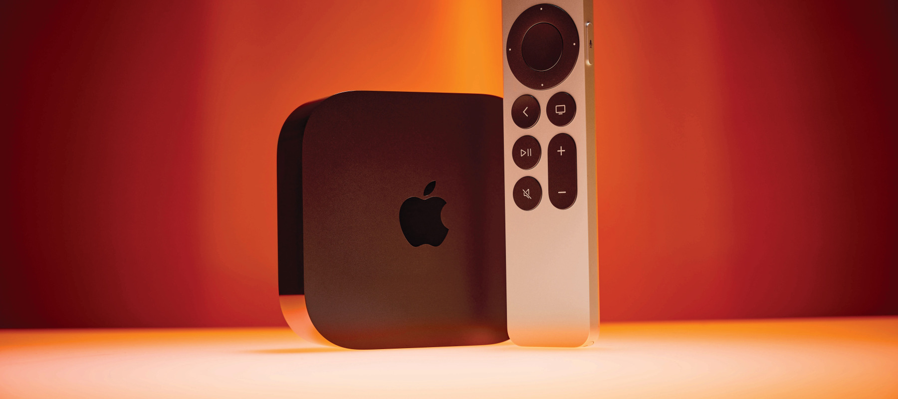 An older generation of the Apple TV 4K box with its remote control.