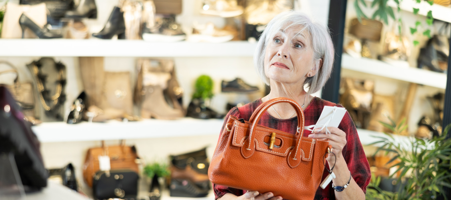 A woman hesitates to buy a new purse at a store.