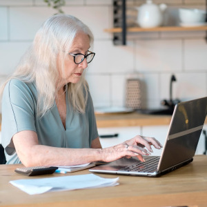 A photo of a woman reviewing her finances on a laptop