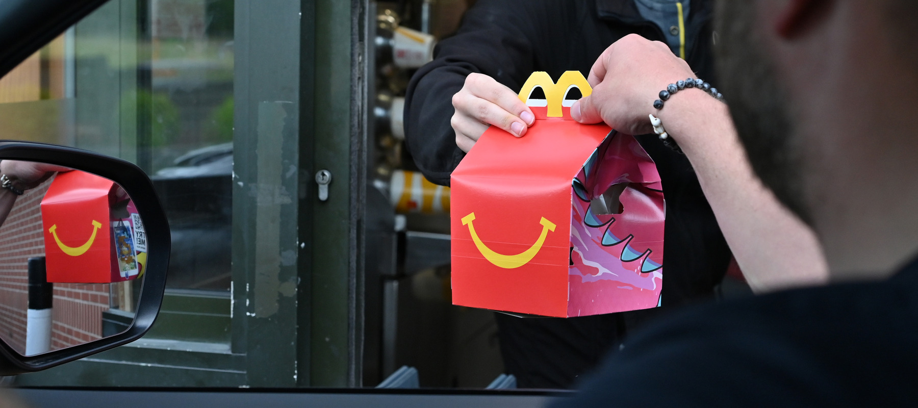 A driver collects a McDonald's Happy Meal order at a drive-through restaurant.