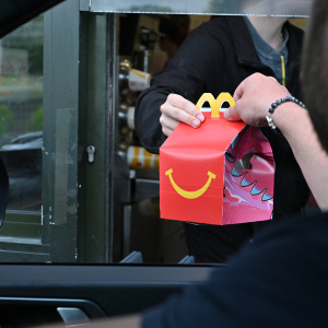 A driver collects a McDonald's Happy Meal order at a drive-through restaurant.