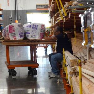 A customer looks at his phone as he sits with his cart at a Home Depot store.