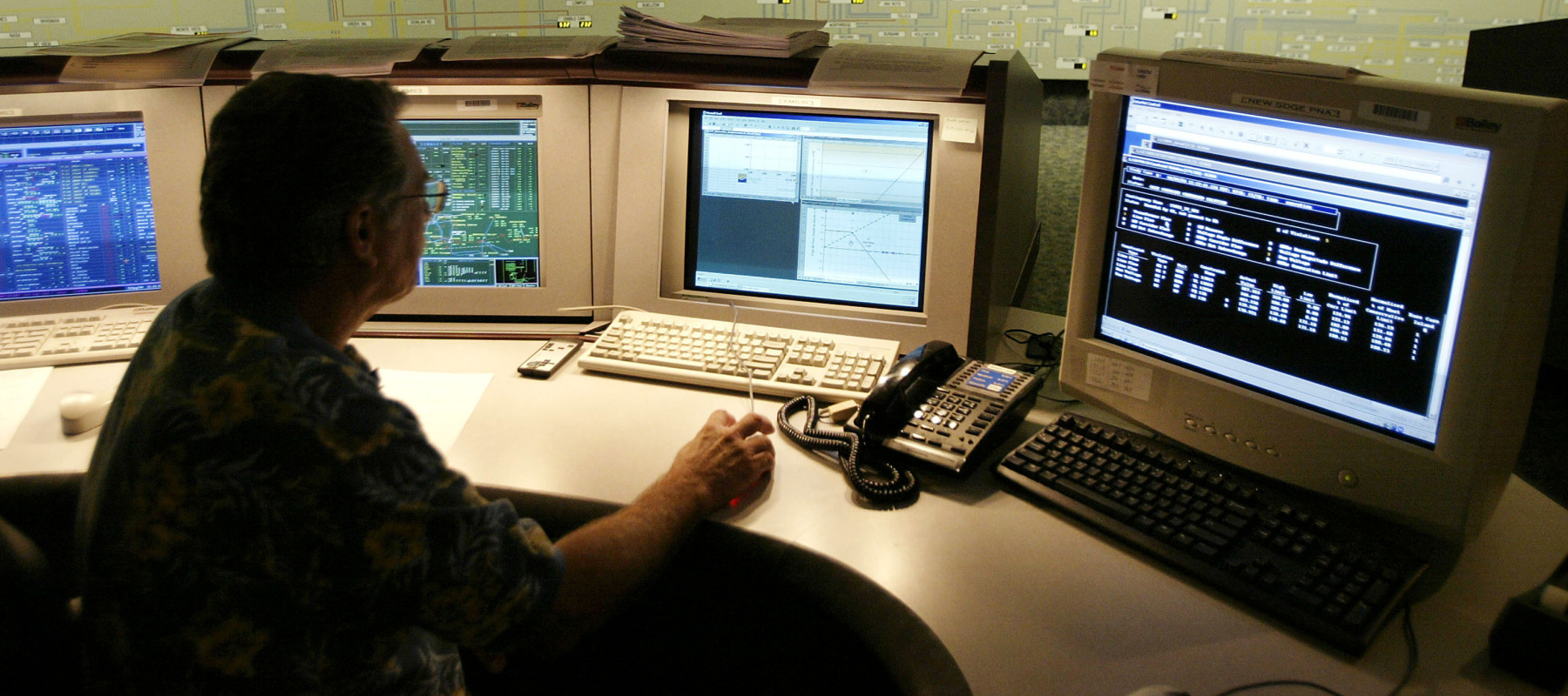 A transmission dispatcher helps manage the flow of electricity near the state map board in the control center of the California Independent System Operator.