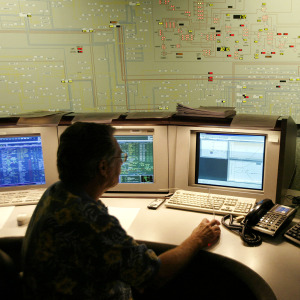 A transmission dispatcher helps manage the flow of electricity near the state map board in the control center of the California Independent System Operator.
