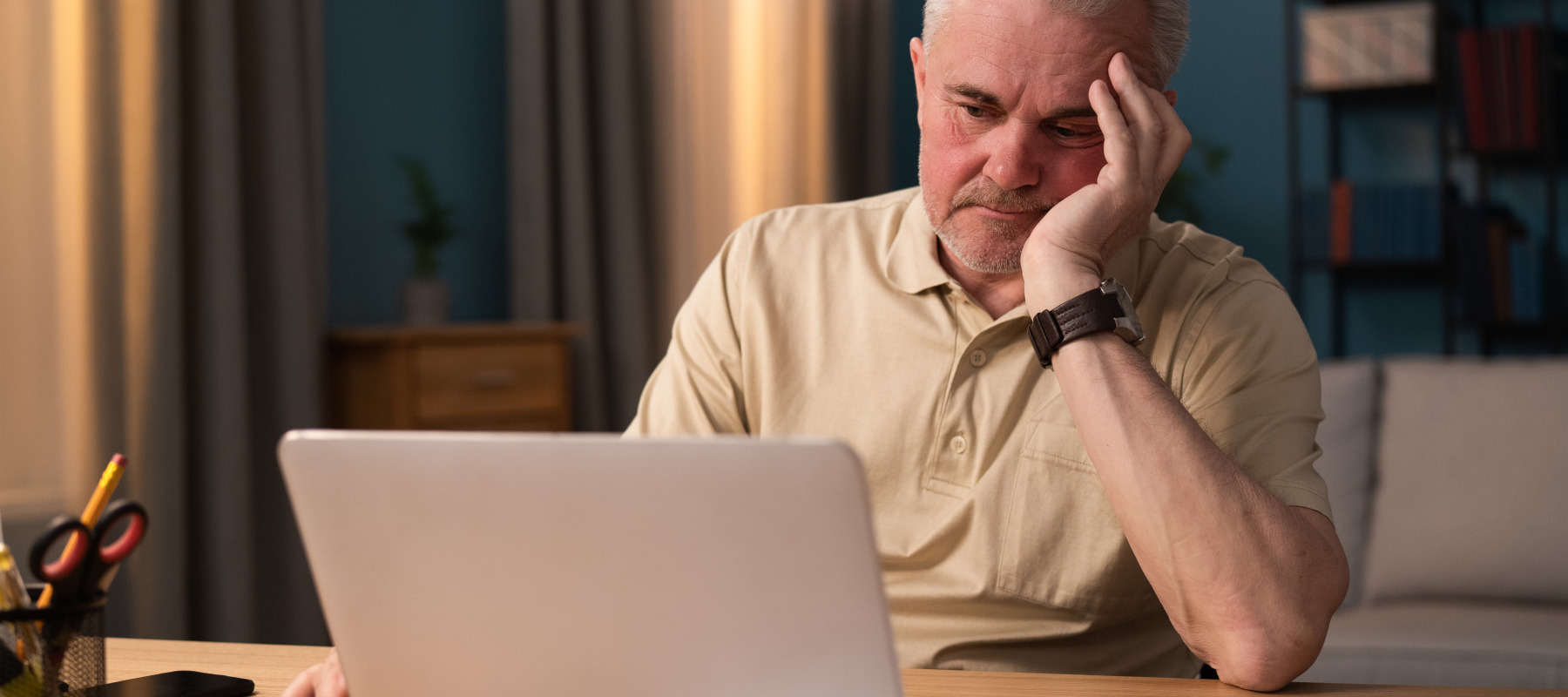 An older American man is frustrated as he looks at his computer.