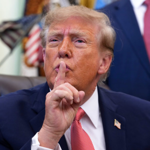 Trump gestures to reporters to be quiet during an event in the Oval Office.