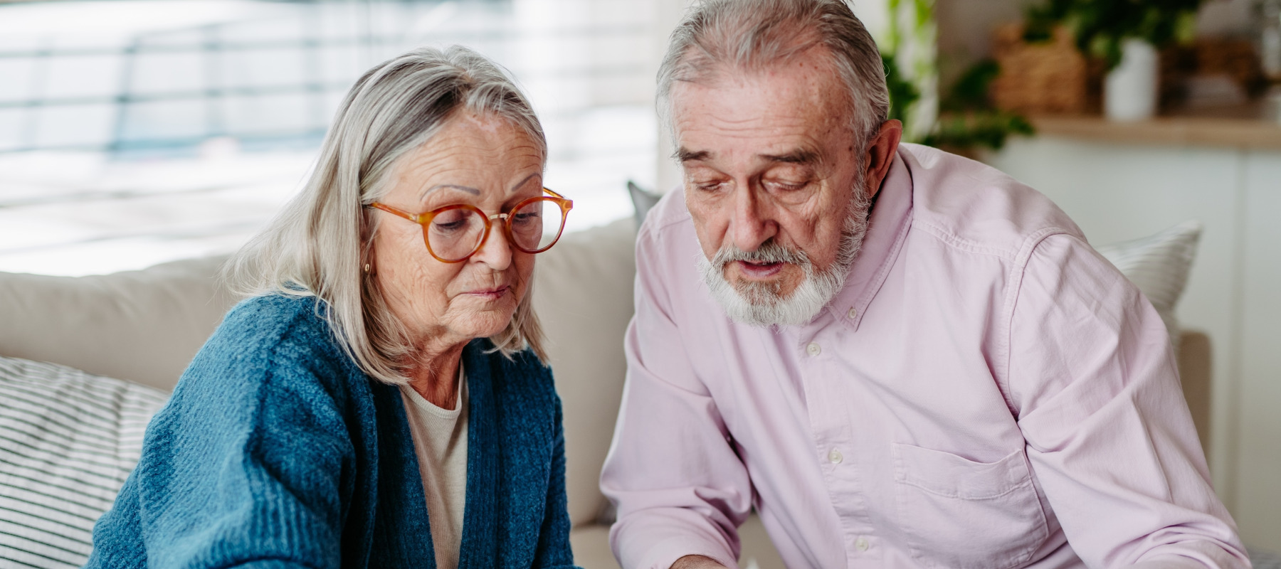 Older couple reviewing papers, serious in thought.