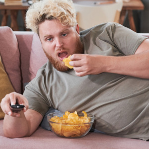 Photo of lazy man on couch eating chips