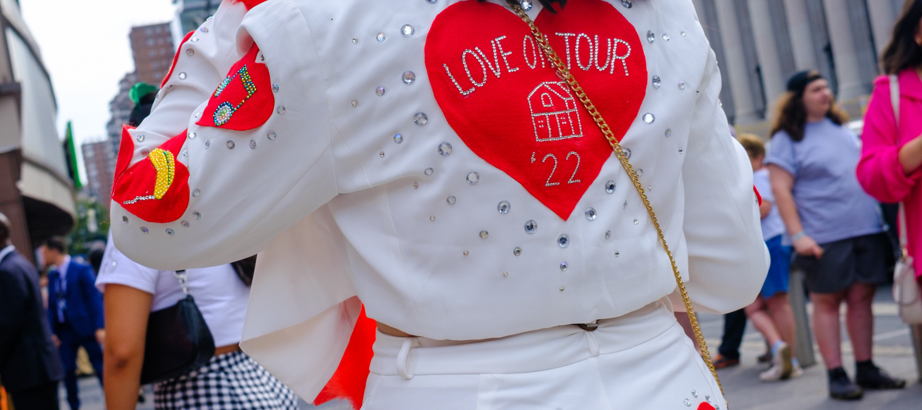 A fan wearing a Harry Styles "Love On Tour" style outfit waits to be admitted.