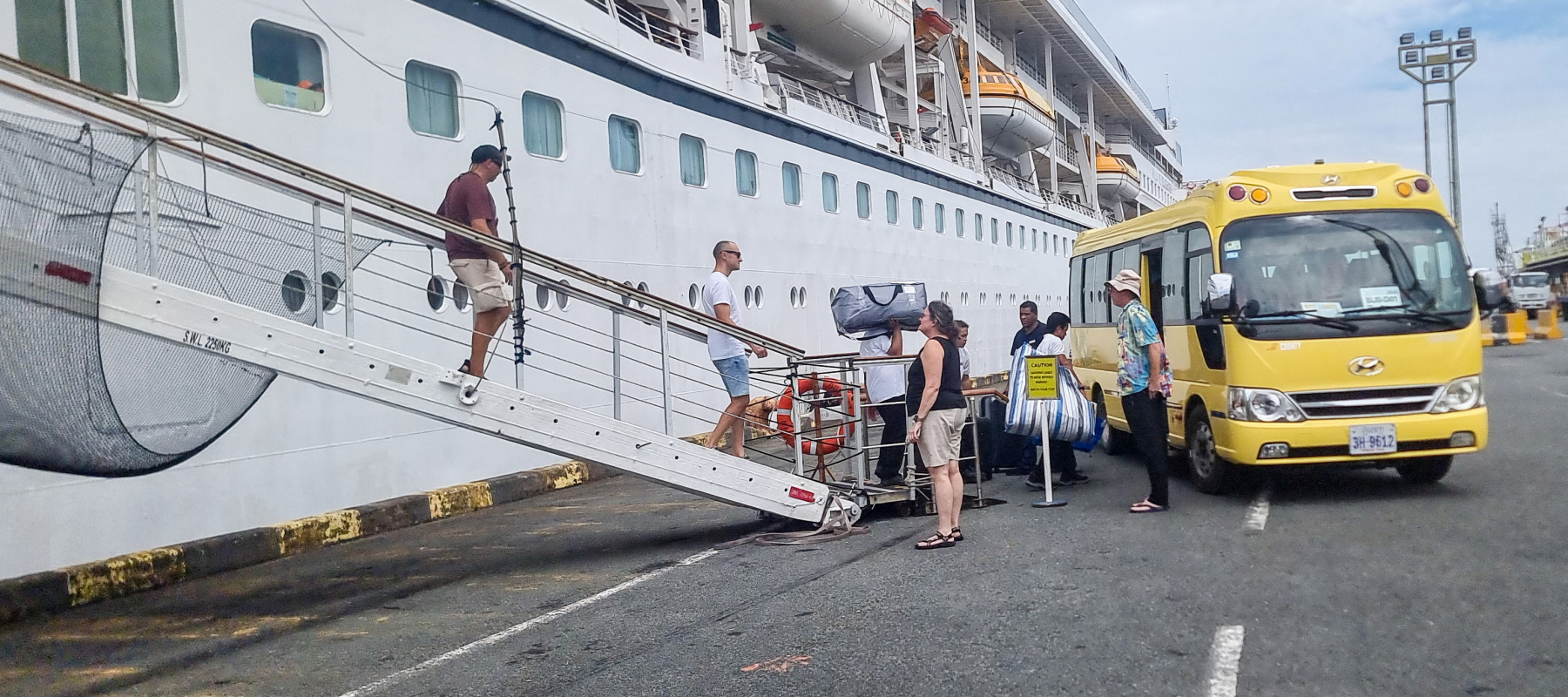 Passengers walk down from the Odyssey cruise ship after 200 passengers were forced to debark in Cambodia due to the company running out of money.
