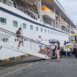 Passengers walk down from the Odyssey cruise ship after 200 passengers were forced to debark in Cambodia due to the company running out of money.