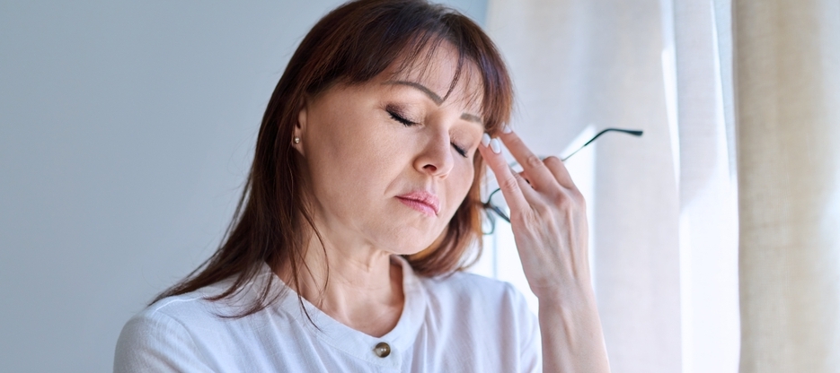 Middle-aged woman experiencing stress with her hand to her forehead.