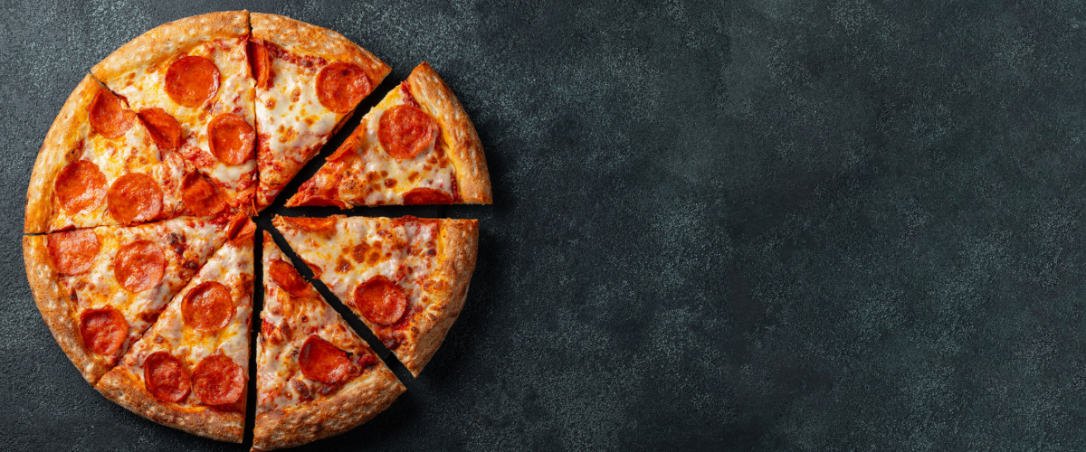 Tasty pepperoni pizza and cooking ingredients tomatoes basil on black concrete background. Top view of hot pepperoni pizza. With copy space for text. Flat lay. Banner