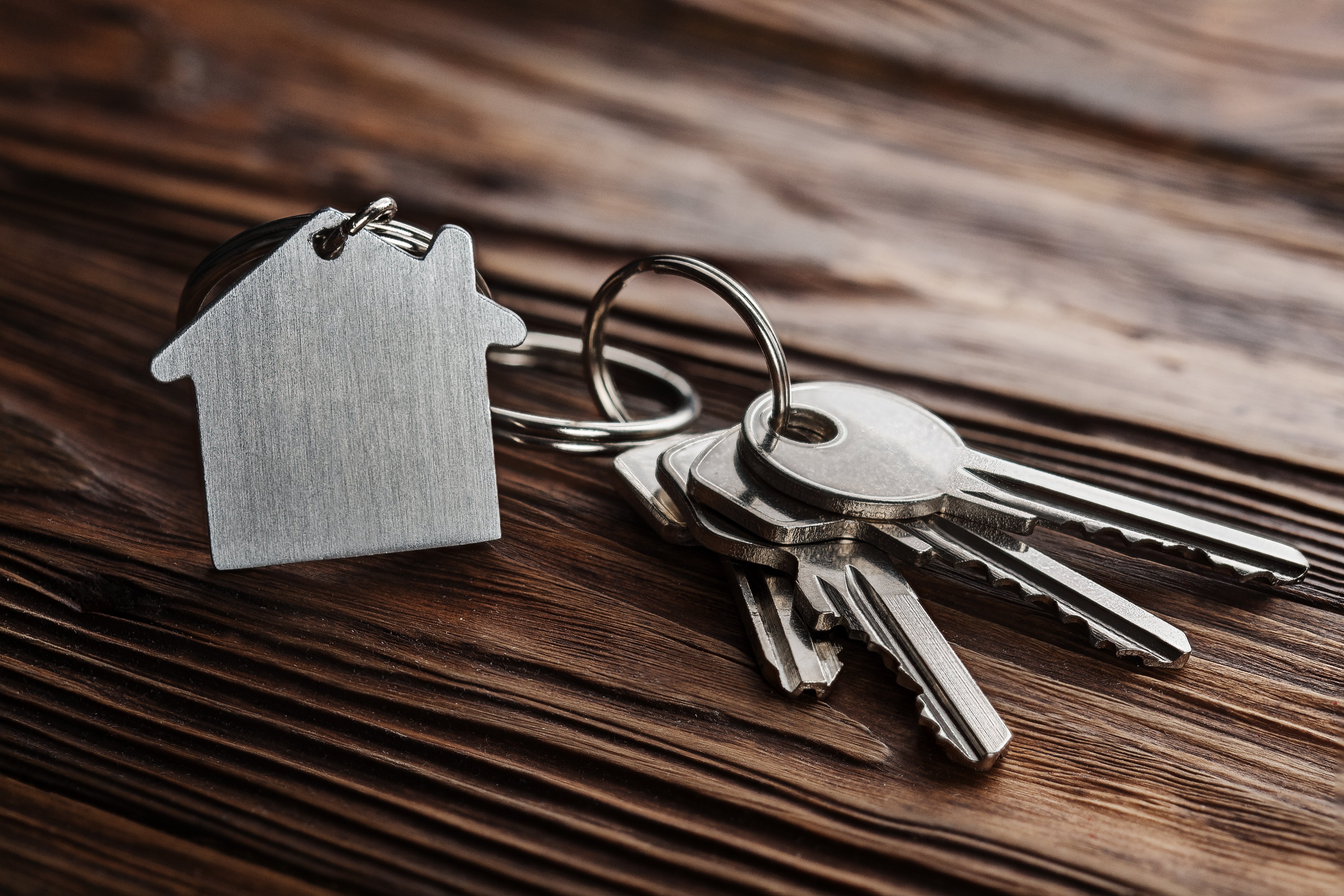 estate concept, keychain with house symbol, key on wooden background