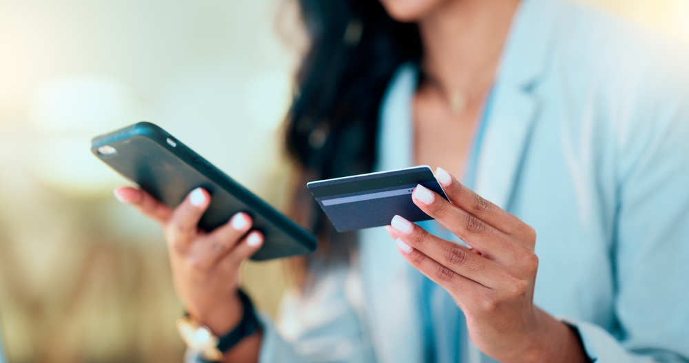 Bank card data put in phone by a lady who does internet banking by typing on her mobile to make an online credit payment. Young woman texting on her phone to send money via an ewallet transaction