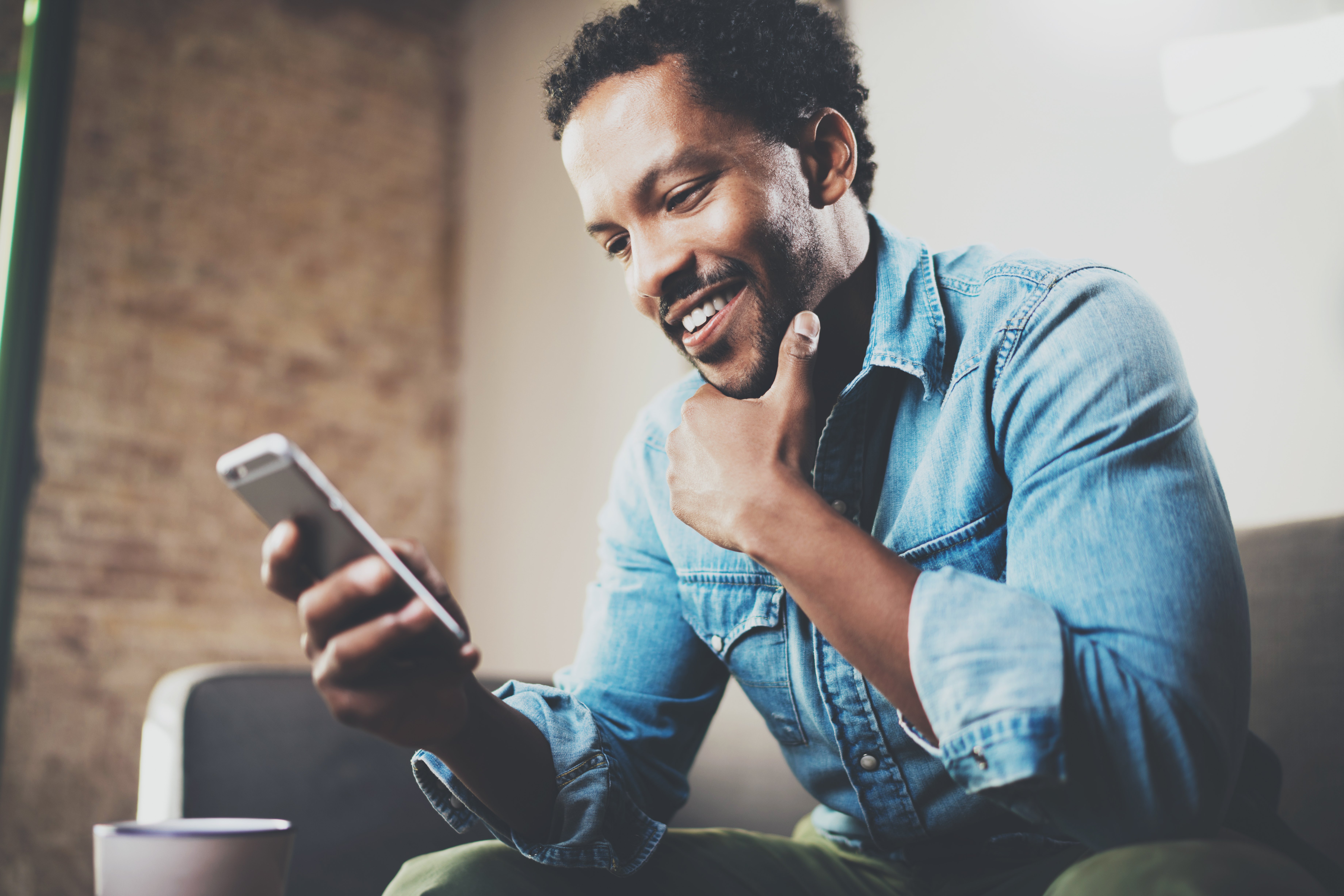 Man smiling holding chin with one hand and phone in the other