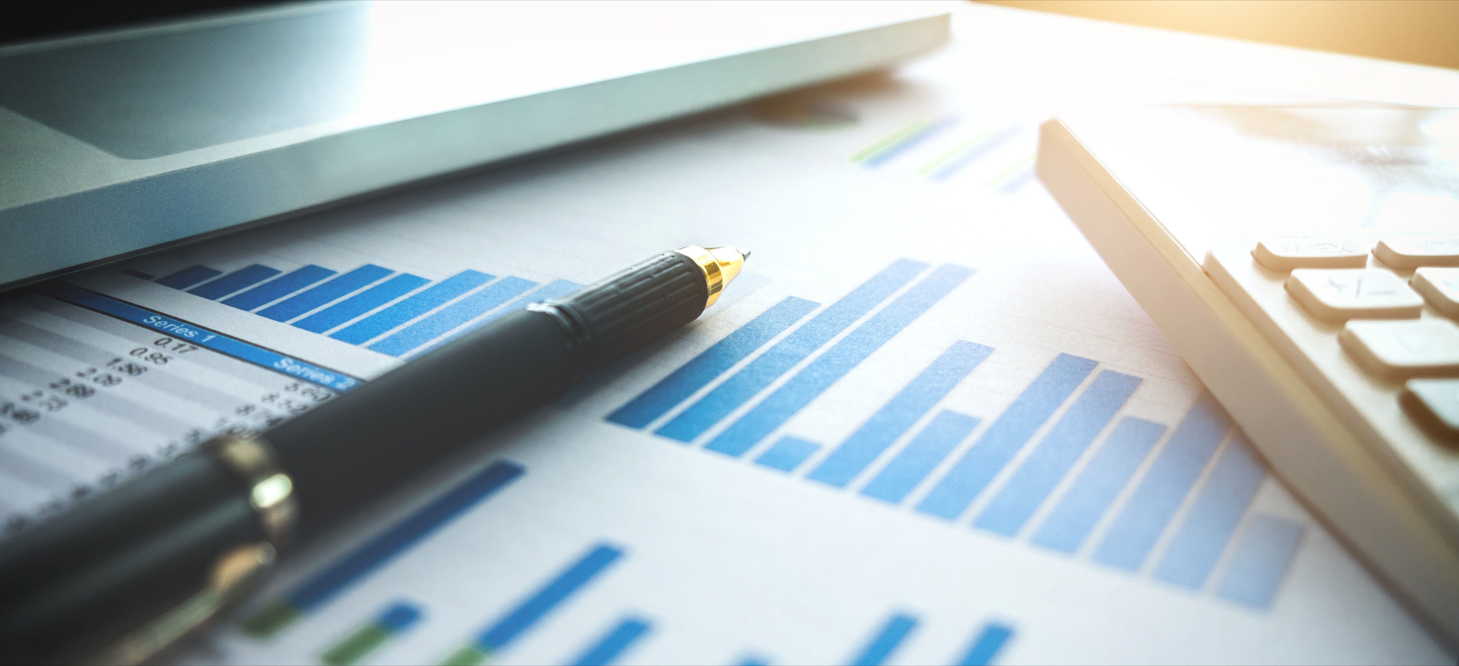 Close up of business pen and white calculator on financial graph data with laptop. finance, saving, investment, business and banking concept.